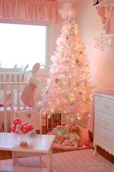 a baby's room decorated in pink and white with a christmas tree on the wall