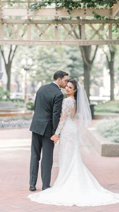 a bride and groom standing under an arbor