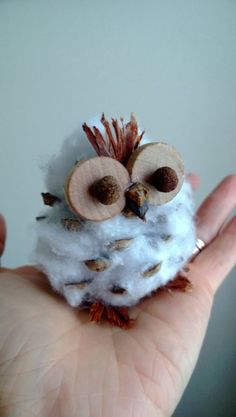 a small stuffed owl sitting on top of a person's hand