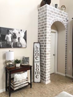 a cat sitting on top of a brick pillar in the middle of a living room