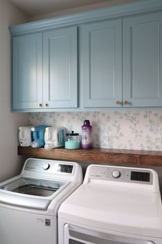 a washer and dryer in a laundry room with blue cabinets on the wall