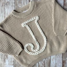 a knit sweater with the letter j on it and an embroidered monogrammed in white thread