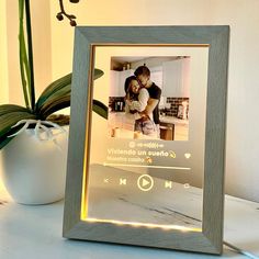 a photo frame with an image of a man and woman in the kitchen next to a potted plant