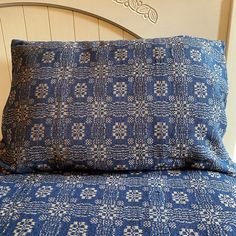 a close up of a bed with a blue comforter and pillow on top of it