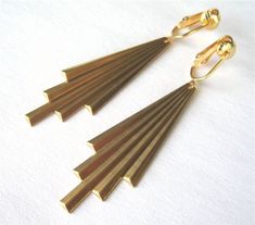 Brass art deco style comet tails hang from gold-plated clip-on ear wires in these dramatic clip on earrings.  The brass piece is lightweight, making these earrings very wearable.The Art Deco clip-ons measure just over 2.75 inches (7cm) from the top of the ear wire.  I've included a photo of them in the palm of my hand to help give an idea of their size.These earrings are shown with simple gold-plated clip-on ear wires.  You can also choose from screw-back gold-plated clip-on ear wires or gold-pl New Necklace Designs, Gold Art Deco Earrings, Brass Art, Ear Clips, Gold Clips, Gold Art Deco, Long Dangle Earrings, Art Deco Earrings, Star Earrings