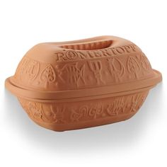 an orange ceramic bowl with ornate designs on the front and sides, sitting on a white surface