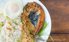 a white plate topped with rice and meat next to an egg on top of it