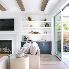 a living room filled with furniture and a flat screen tv mounted on a wall above a fire place