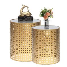 two gold metal side tables with flowers in vases on top and one has a deer figurine