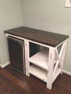 a white and brown wooden cabinet sitting on top of a hard wood floor next to a wall