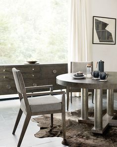 a dining room table with two chairs and a rug on the floor in front of it