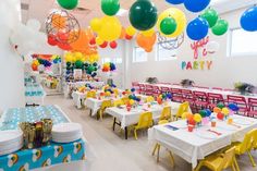 a room filled with lots of tables covered in colorful balloons and plates on top of them