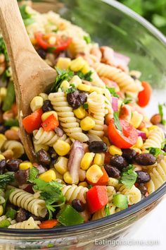 a bowl filled with pasta salad and a wooden spoon