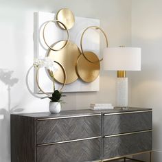 a modern sideboard with gold circles on it and a white flower in a vase