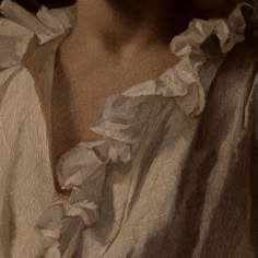 a close up view of a woman's face wearing a white shirt with ruffles