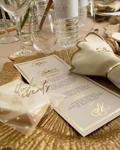 the table is set with white and gold place settings, napkins, and wine glasses