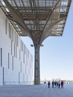 people are walking under a large structure in the middle of an open air area with white walls