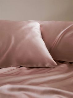 a bed with pink sheets and pillows on it