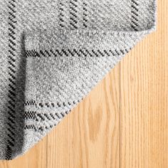 a gray and black rug on top of a wooden floor next to a wood floor