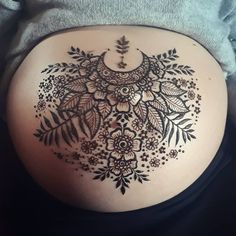 a woman's stomach with an intricate tattoo on it