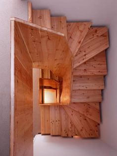 an overhead view of a wooden staircase with light at the top and bottom, looking down