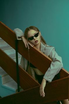 a woman wearing sunglasses leaning on a wooden rail