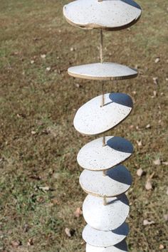 a wind chime made out of rocks on top of some grass with leaves in the background