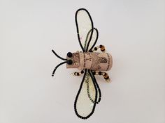 an insect made out of wine corks and beaded beads on a white background