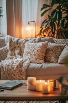 a living room with candles on the coffee table and a blanket draped over the couch