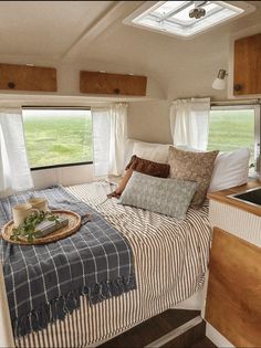 a bed in a trailer with pillows and blankets on top of the bedspread