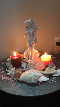 a table topped with candles and seashells next to a statue on top of it