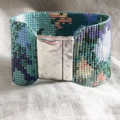 a close up of a bracelet on a white surface with a metal clasp and square beads