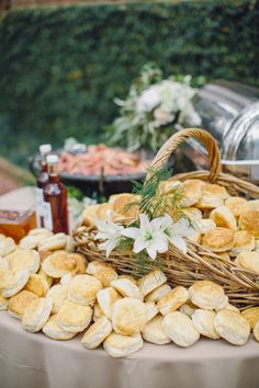 a table topped with lots of food next to a basket filled with bread and flowers