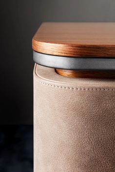 an upholstered leather stool with a wooden top and metal trim around the seat