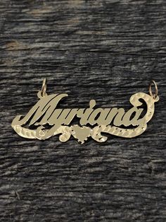 the name necklace is engraved on top of a piece of wood with an ornate design