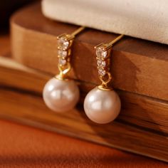 Crafted from the finest freshwater pearls, this jewel's warm luster will take you from a sparkling dinner party to everyday loung. It's not just the finishing touch to your outfit, it's a natural expression of your elegance. Whether it's the joy of celebrating a birthday, the warmth of remembering an anniversary, or any memorable moment, it is a unique gift that will deeply express your appreciation and blessings to the recipient. Its simple yet elegant design makes every wear a whisper of beaut Pearl Embellished Cubic Zirconia Earrings As Gift, Gift Pearl Earrings With Cubic Zirconia, Pearl Charm Earrings With Cubic Zirconia As Gift, Party Pearl Pendant Earrings, Elegant Pearl White Pearl Earrings As Gift, Pearl Anniversary Earrings, Anniversary Pearl White Earrings With Pearl Pendant, Anniversary Pearl Drop Earrings With Pendant, Round Pearl Pendant Earrings For Party