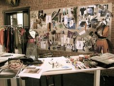 a table with many items on it in front of a brick wall and several windows