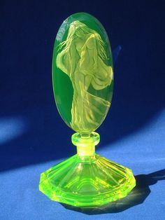 a green glass vase sitting on top of a blue table