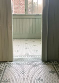 an open door leading to a bathroom with white and green tiles on the flooring