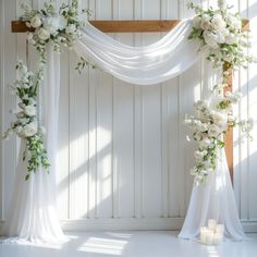 a wedding arch decorated with white flowers and greenery