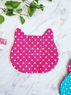 a pair of flip flops sitting on top of a white marble counter next to a pink and blue polka dot kitty