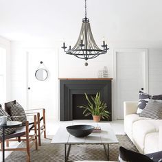 a living room filled with furniture and a chandelier hanging over the fire place