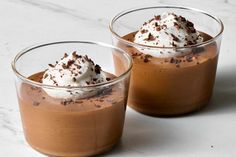 two glasses filled with dessert sitting on top of a white counter next to each other