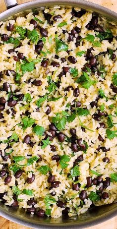 rice with black beans and cilantro in a pan on a wooden table top