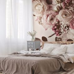 a bed sitting under a window next to a flower covered wall mural in a bedroom