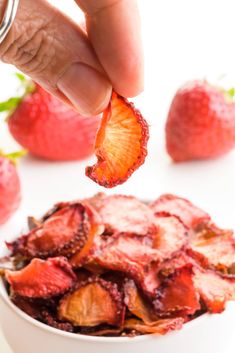 someone is picking up some strawberries from a bowl