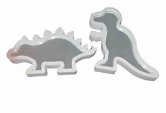 two cookie cutters shaped to look like dinosaurs, one is grey and the other is white