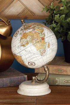 a globe sits on top of a table next to books and a potted plant