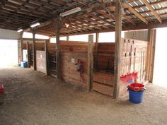 the inside of a horse barn with stalls and buckets