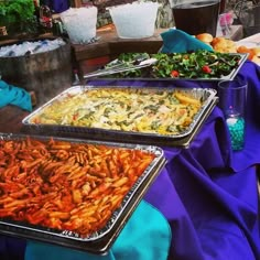 several trays of food sitting on top of a blue table cloth covered tablecloth